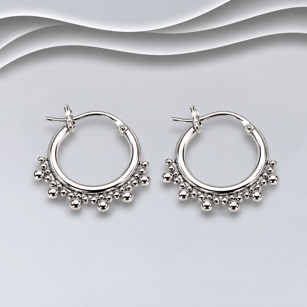 Pair of polished sterling silver hoop earrings with beaded detailing along the lower edge and hinged fastenings
